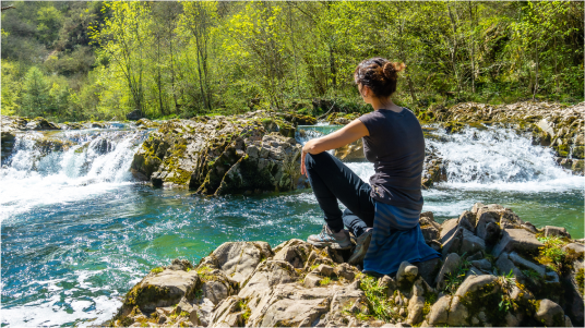 Bild Frau schaut auf kleinen Wasserfall